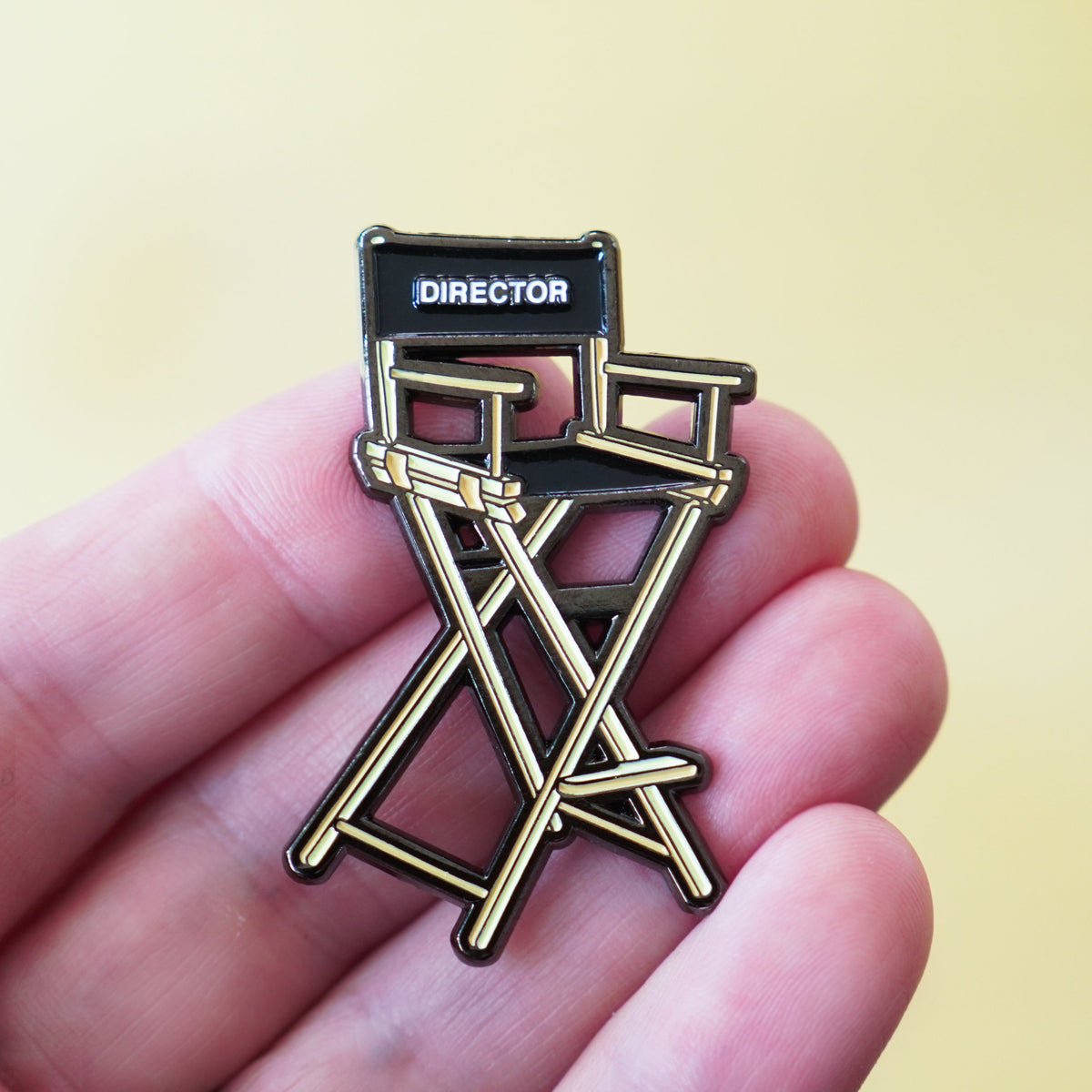 Director's Chair Enamel Pin in hand